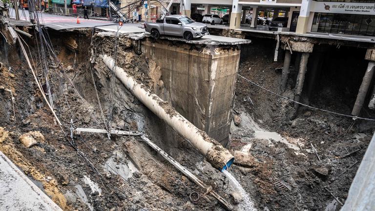 A vehicle is seen on the edge of a hole in the ground after a road collapsed near a hospital in Bangkok on September 24, 2025. 