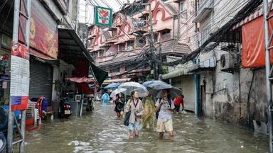 Menschen waten in Bangkok durch überflutete Straßen. (26. September 2026)