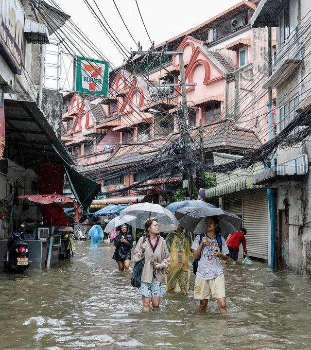 Menschen waten in Bangkok durch überflutete Straßen. (26. September 2026)