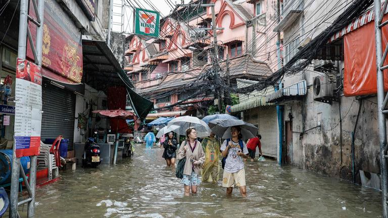 Menschen waten in Bangkok durch überflutete Straßen. (26. September 2026)