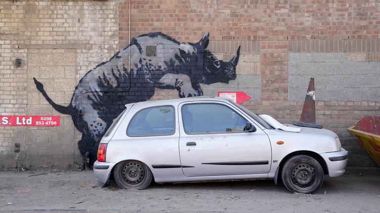 Ein neues Banksy-Kunstwerk. Ein Nashorn, dass auf ein Auto "klettert"