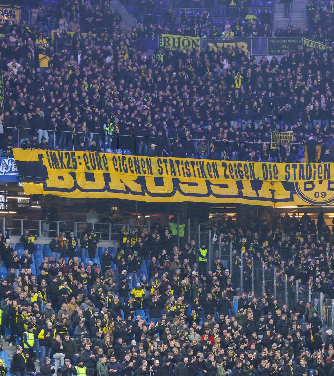 Fans von Borussia Dortmund halten einen großen Banner in der Fankurve nach oben am 08.11.2025.