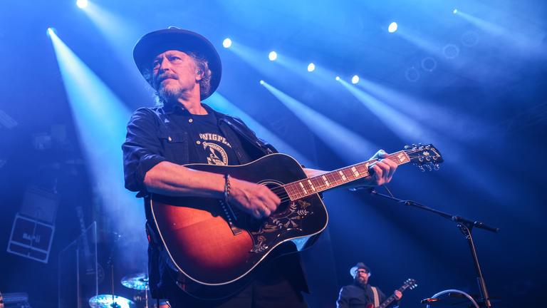 Sänger Wolfgang Niedecken von der Band BAP spielt Giratte auf der Bühne. 