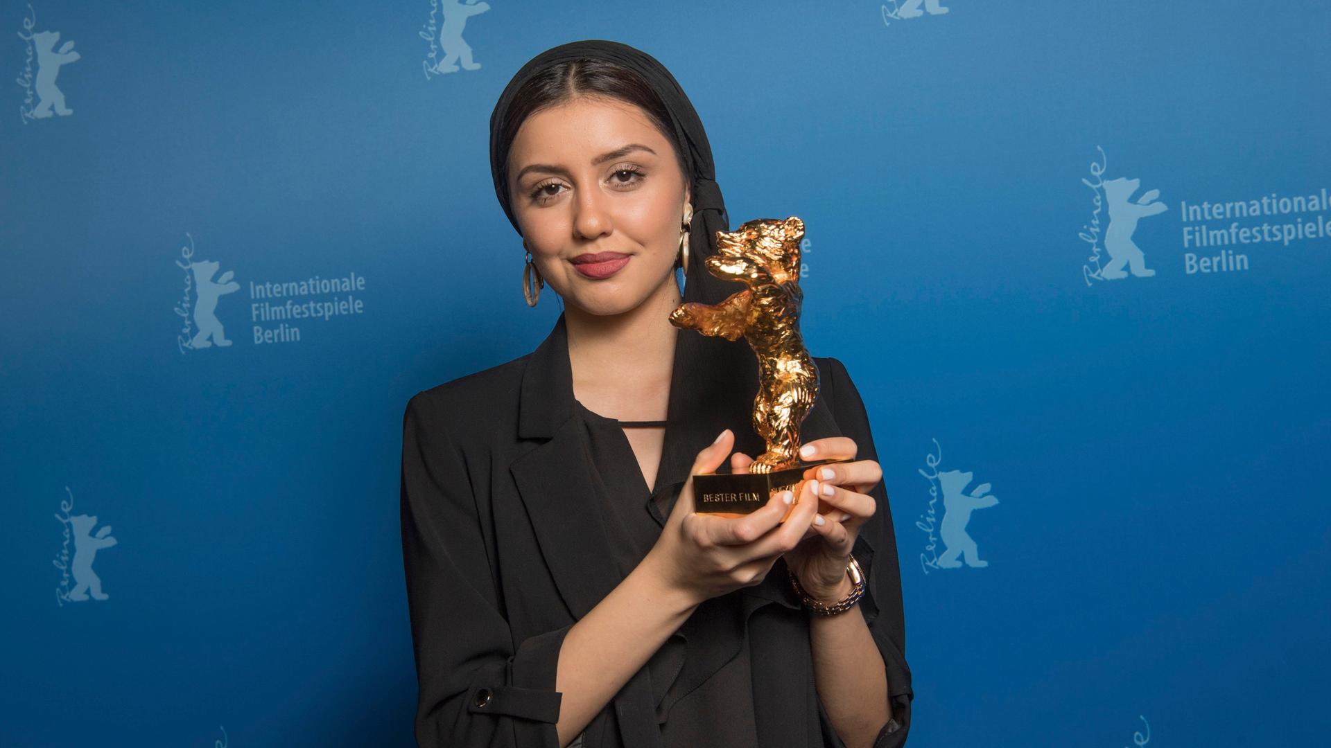 Baran Rasoulof hält einen goldenen Bären in den Händen und lächelt in die Kamera