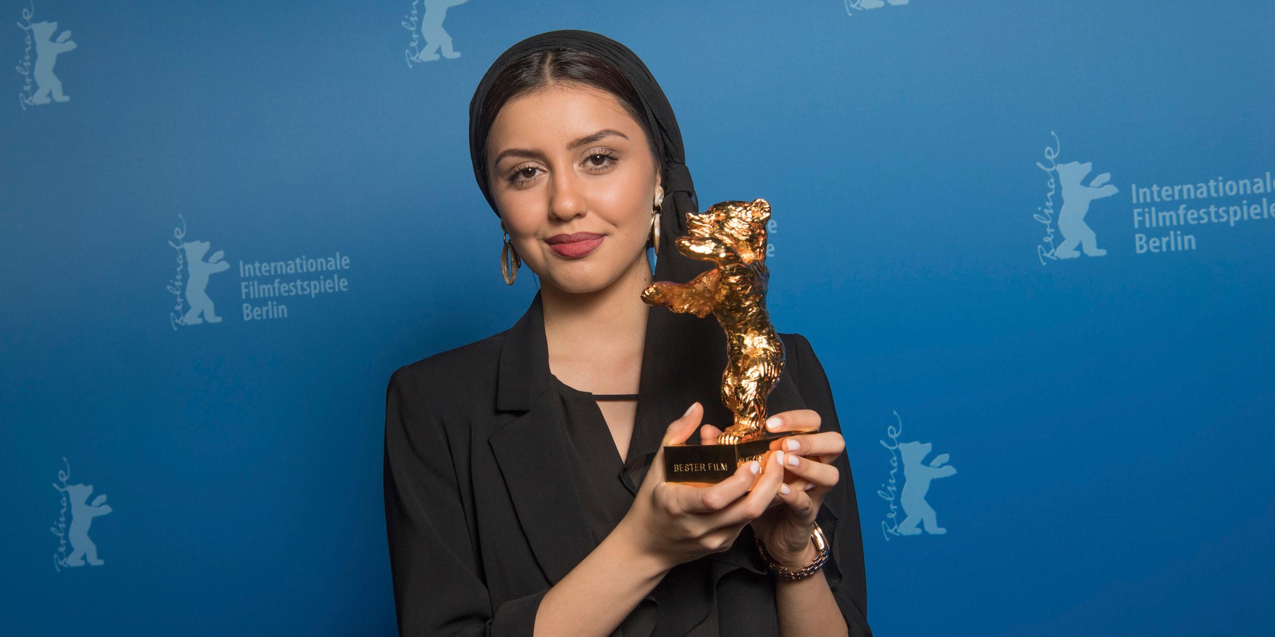 Baran Rasoulof hält einen goldenen Bären in den Händen und lächelt in die Kamera