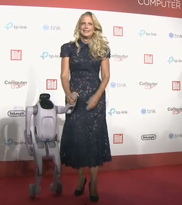 Auf dem Bild zu sehen ist: in einer Halbtotalen Barbara Schöneberger und ein Roboter