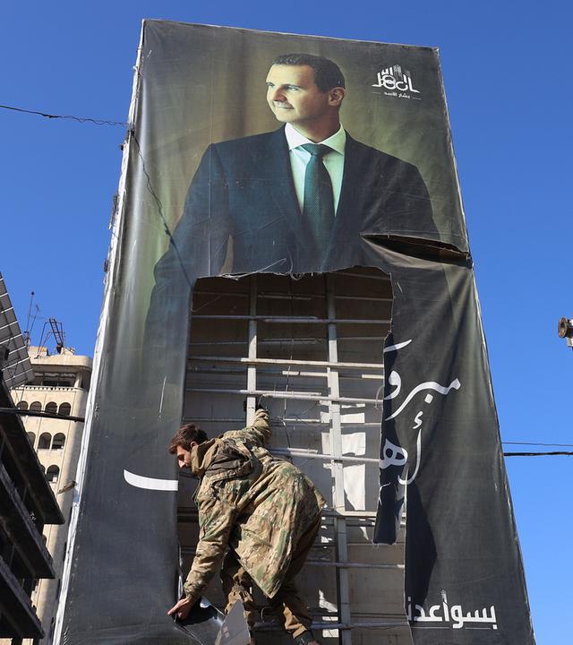 Kämpfer der Opposition zerreißen ein riesiges Porträt des syrischen Präsidenten Baschar al-Assad in Aleppo (Syrien)