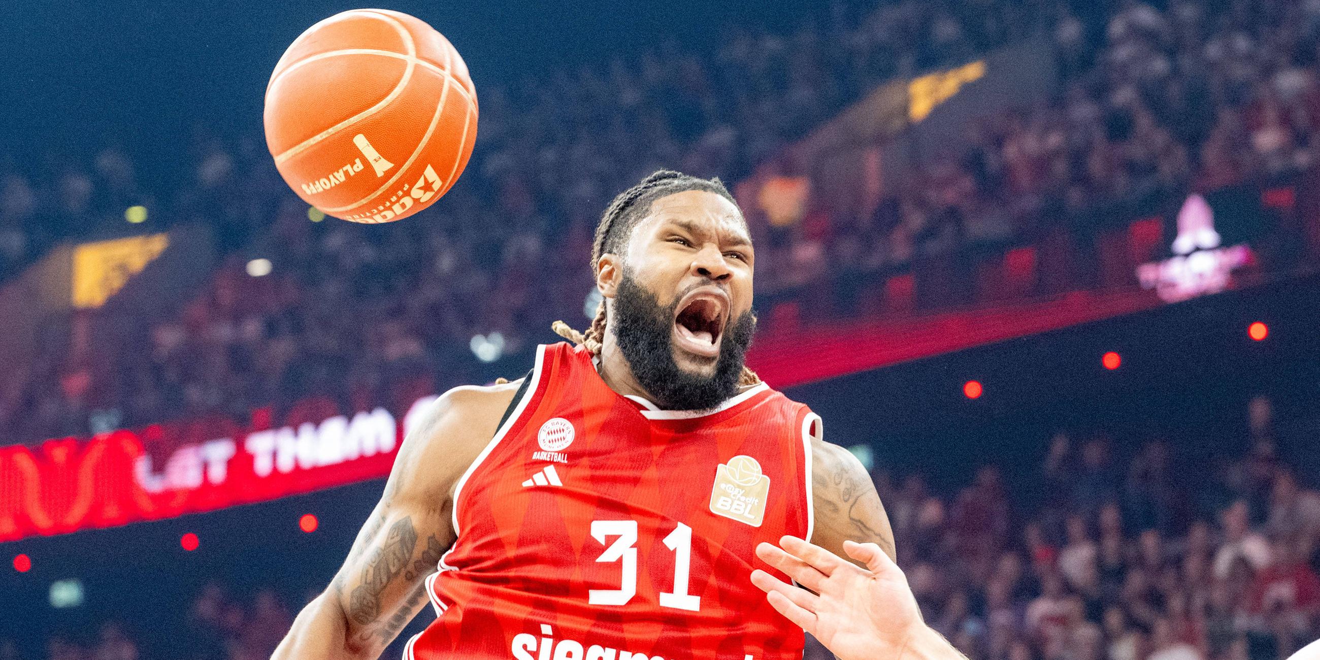 Devin Booker von FC Bayern Basketball brüllt während dem Spiel gegen Ratiopharm Ulm. Ein Basketball fliegt neben seinem Kopf vorbei.