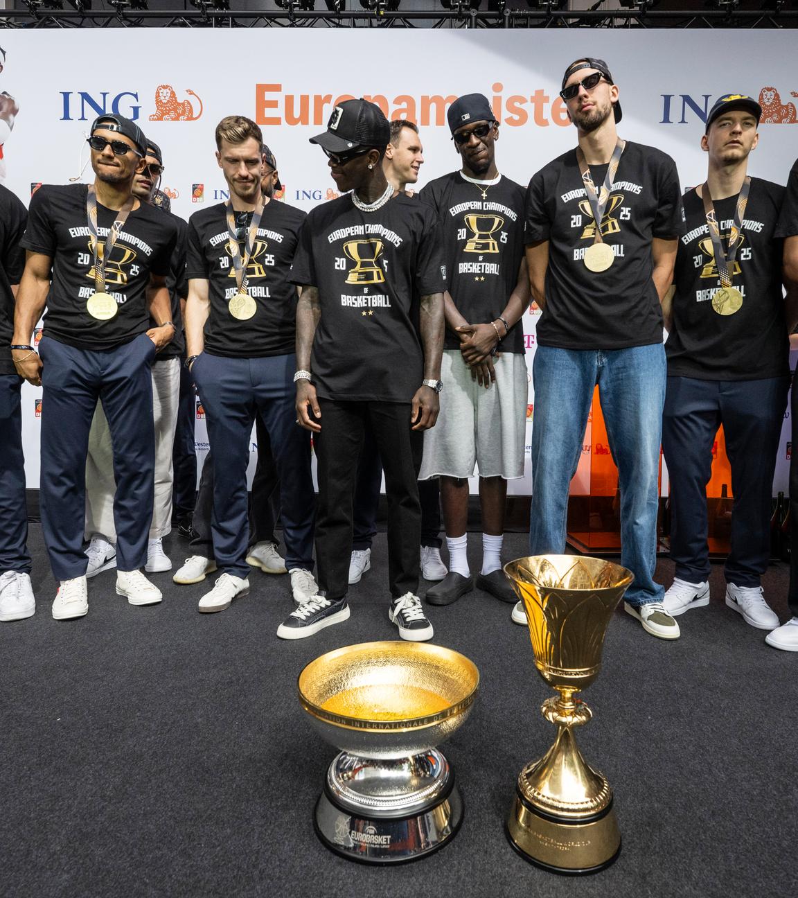 Deutschlands Team steht vor der WM- und der EM-Trophäe, (v.l.) Assistentstrainer Alan Ibrahimagic, Maodo Lo, Andreas Obst, Dennis Schröder, Johannes Voigtmann (M/hinten), Isaac Bonga, Franz Wagner, Justus Hollatz und Tristan Da Silva. 