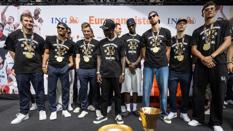 Deutschlands Team steht vor der WM- und der EM-Trophäe, (v.l.) Assistentstrainer Alan Ibrahimagic, Maodo Lo, Andreas Obst, Dennis Schröder, Johannes Voigtmann (M/hinten), Isaac Bonga, Franz Wagner, Justus Hollatz und Tristan Da Silva. 