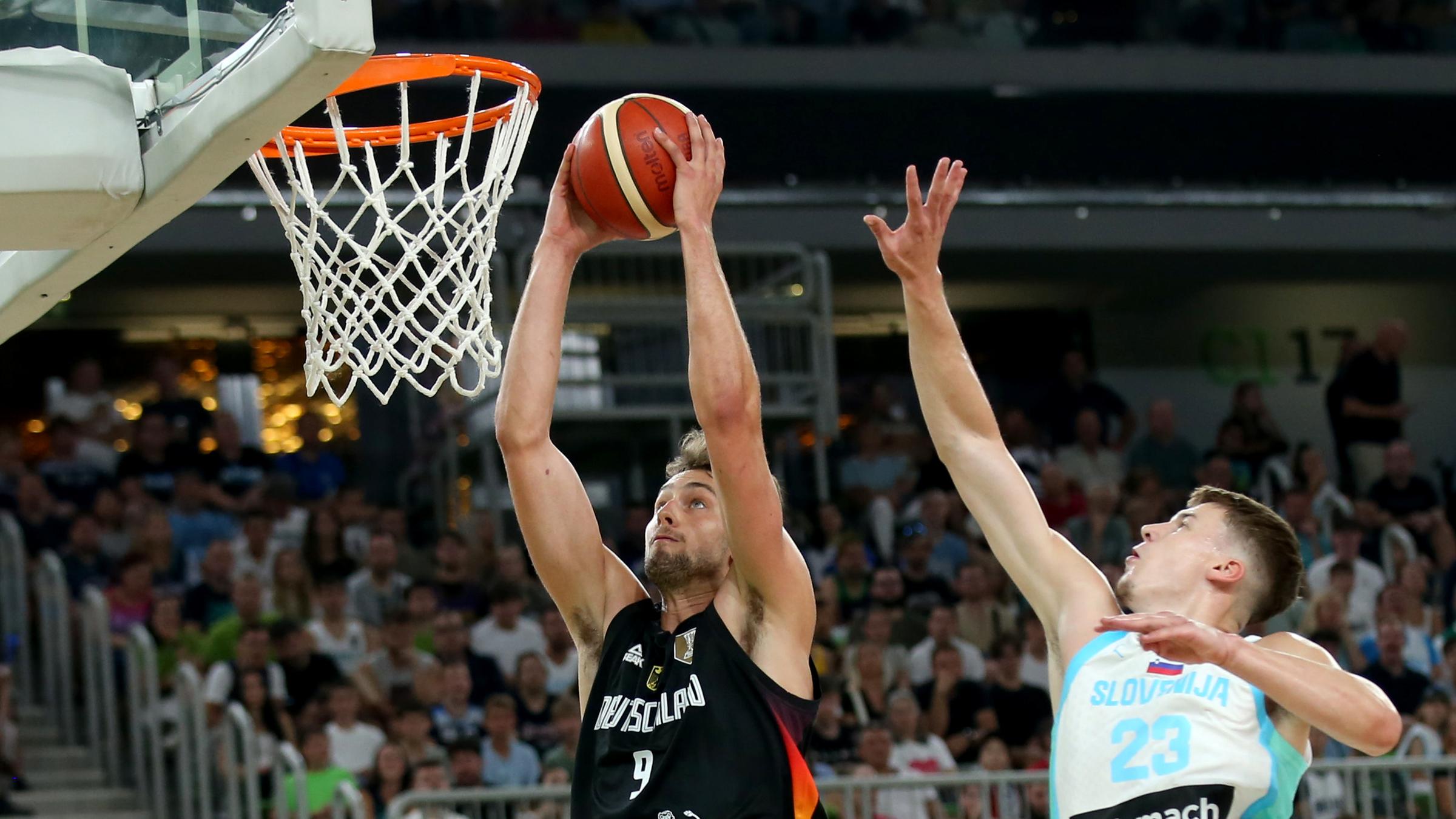 Basketballer Franz Wagner (l, Deutschland) zieht gegen Luka Scuka (Slowenien) zum Korb am 08.08.2025 Ljubljana, Slowenien.