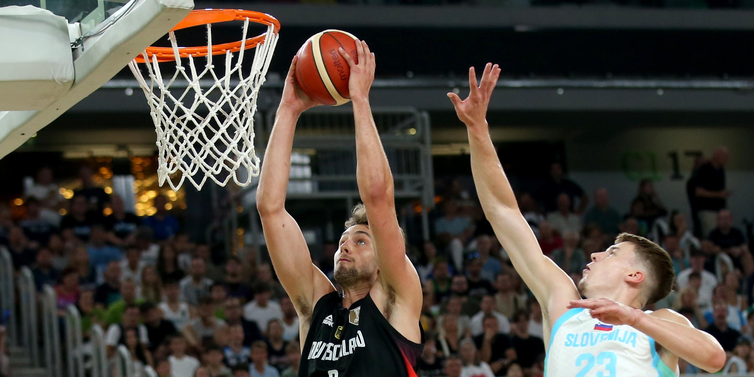 Basketballer Franz Wagner (l, Deutschland) zieht gegen Luka Scuka (Slowenien) zum Korb am 08.08.2025 Ljubljana, Slowenien.