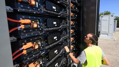 EIn Mitarbeiter blickt in einen offenen Batteriespeicher