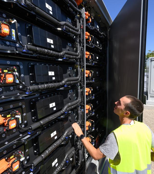 EIn Mitarbeiter blickt in einen offenen Batteriespeicher