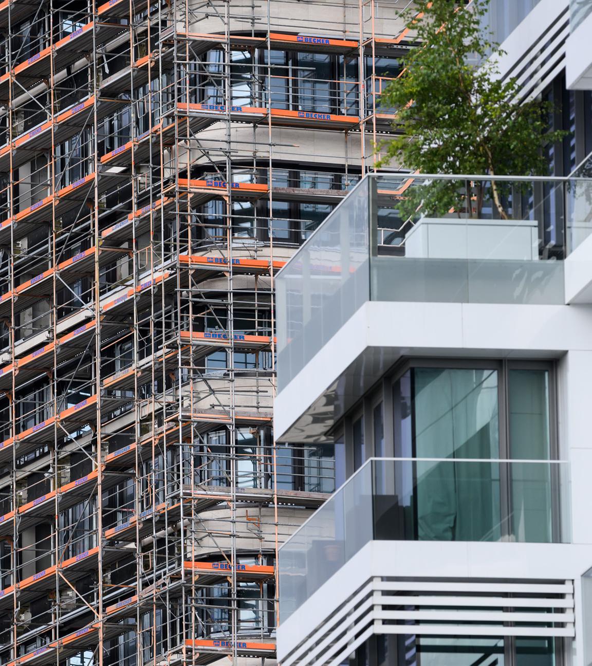 Hinter einem Wohn-Hochhaus mit hochwertigen Luxus-Eigentumswohnungen am Spreeufer in Friedrichshain entstehen neue Gebäude, die noch von Baugerüsten verdeckt sind.