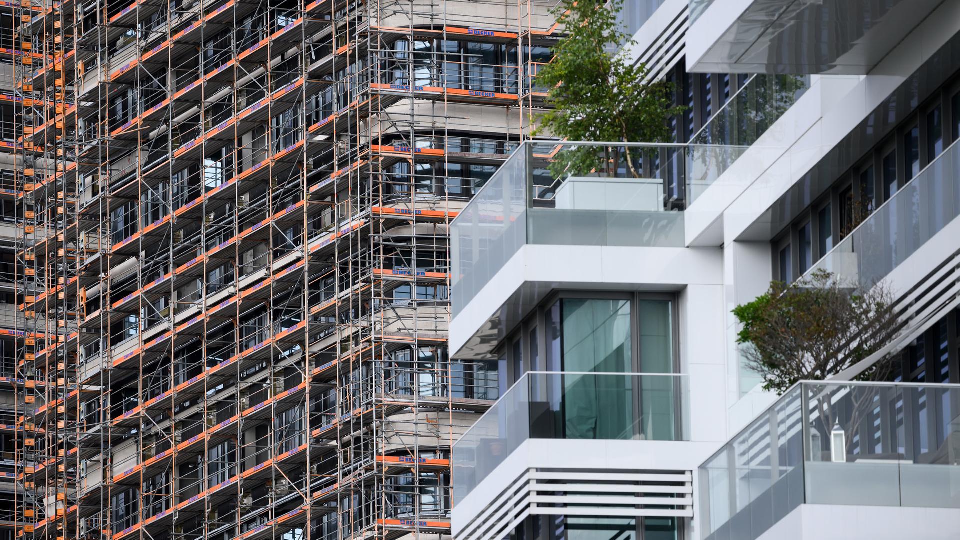 Hinter einem Wohn-Hochhaus mit hochwertigen Luxus-Eigentumswohnungen am Spreeufer in Friedrichshain entstehen neue Gebäude, die noch von Baugerüsten verdeckt sind.
