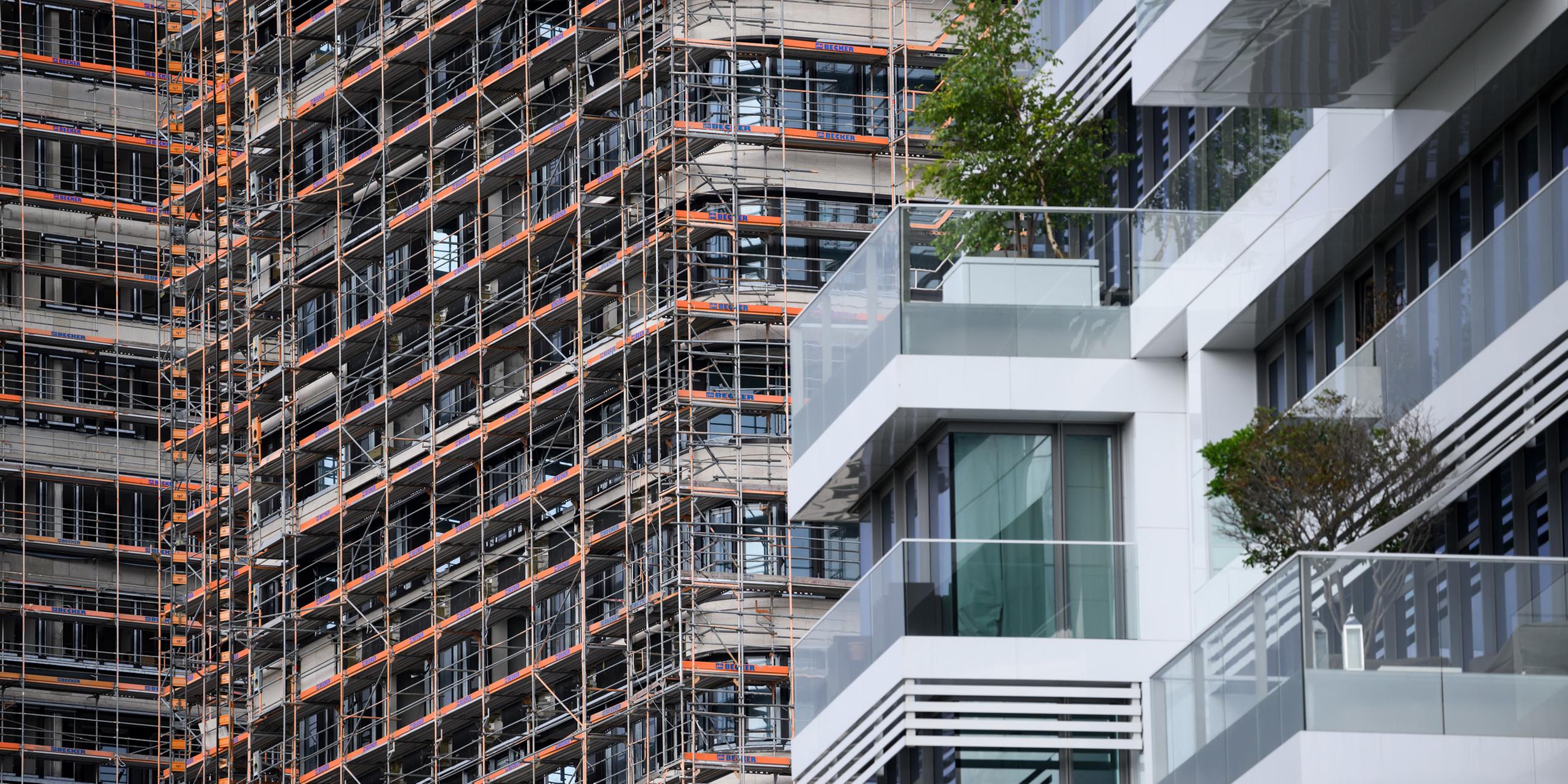 Hinter einem Wohn-Hochhaus mit hochwertigen Luxus-Eigentumswohnungen am Spreeufer in Friedrichshain entstehen neue Gebäude, die noch von Baugerüsten verdeckt sind.