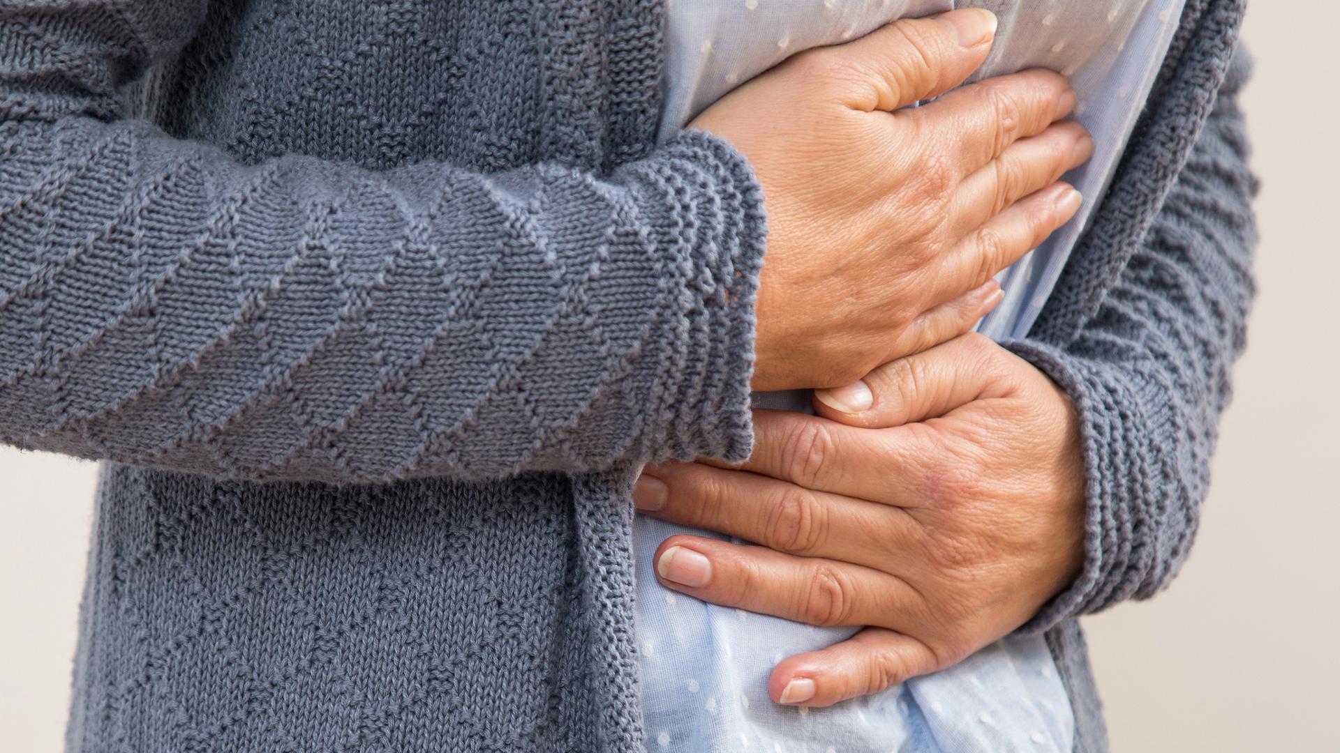 Frau hält sich wegen Magenschmerzen den Bauch fest.