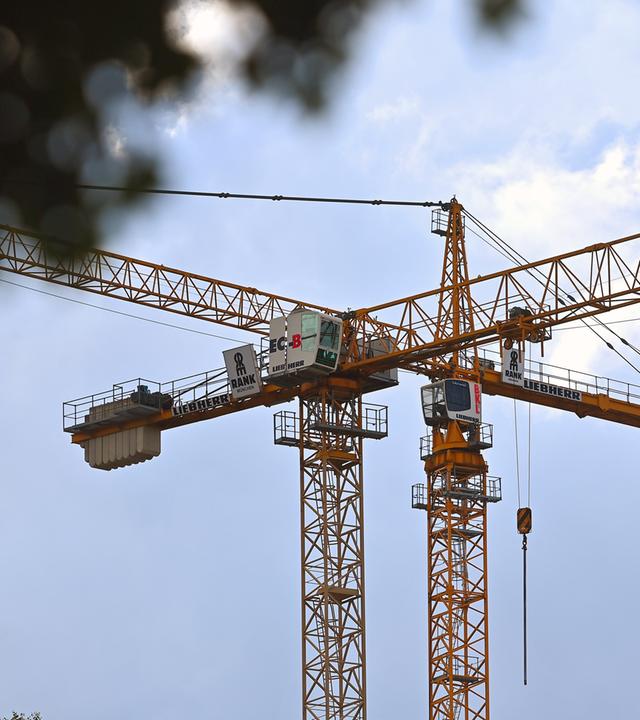 Zwei Baukräne der Firma Liebherr auf einer Baustelle.