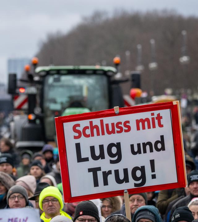 Teilnehmer der durch die Interessenvertretung Freie Bauern angemeldeten Kundgebung stehen mit Schildern und Flaggen auf der Straße des 17. Juni vor dem Brandenburger Tor