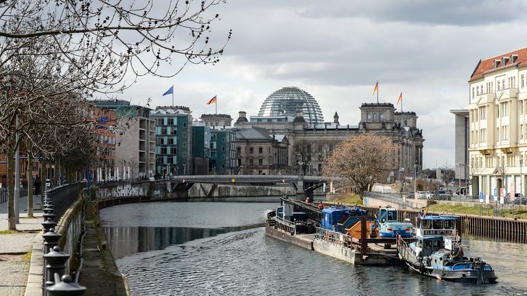 Auf einer Arbeitsplattform werden ein Bagger und ein eingeklappter Kran auf der Spree von einer Baustelle am Schiffbauerdamm in Richtung Reichstag weggefahren.