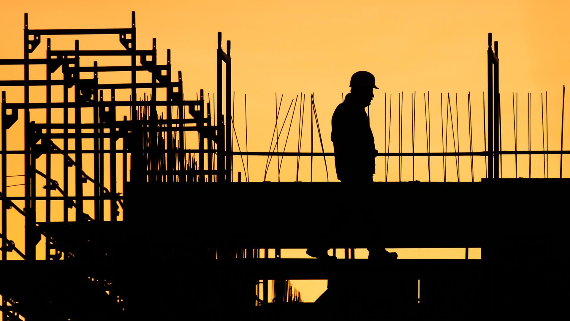 Archiv: Ein Bauarbeiter geht auf einer Baustelle für ein Gebäude, während die sonne aufgeht. Aufgenommen am 13.02.2020 in Hannover.