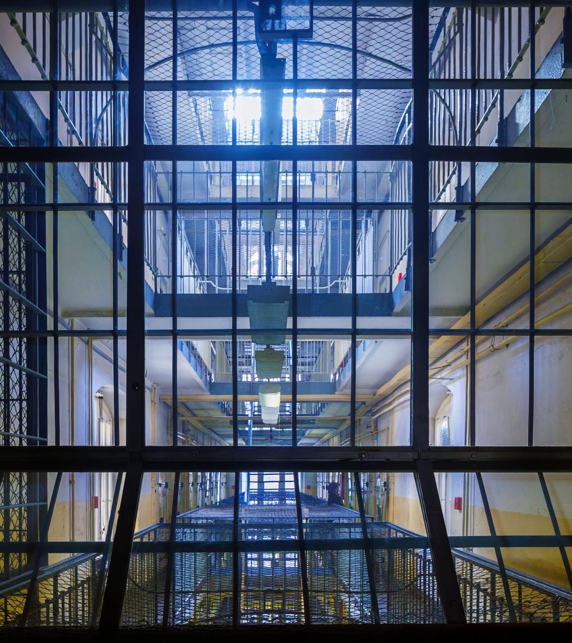 Blick durch ein Gitter in einen Gefängnisinnenhof.