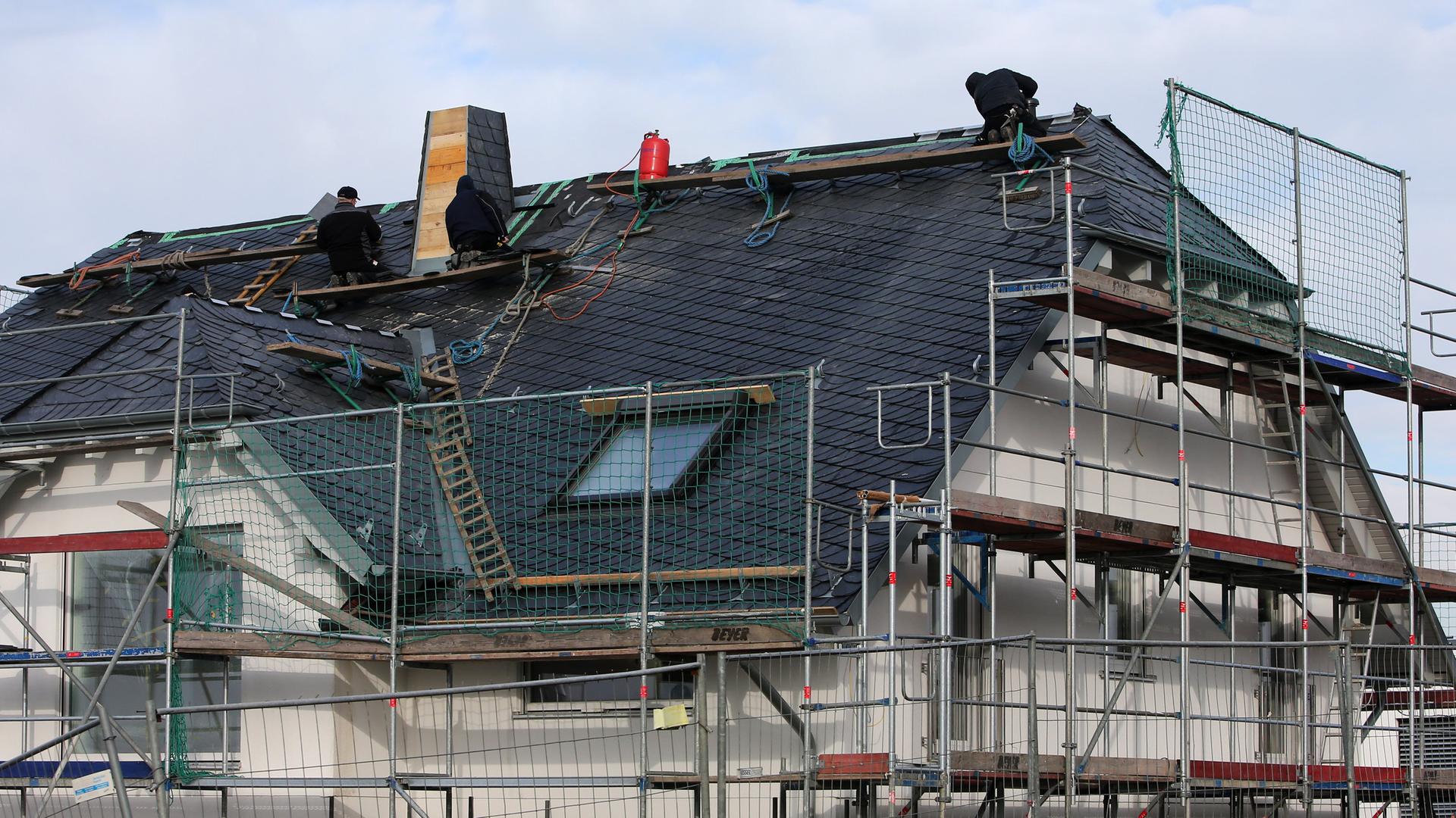 Männer arbeiten in einem Neubaugebiet in Nieder-Olm (Rheinland-Pfalz) am Dach eines Neubaus (Symbolbild Bauzinsen).