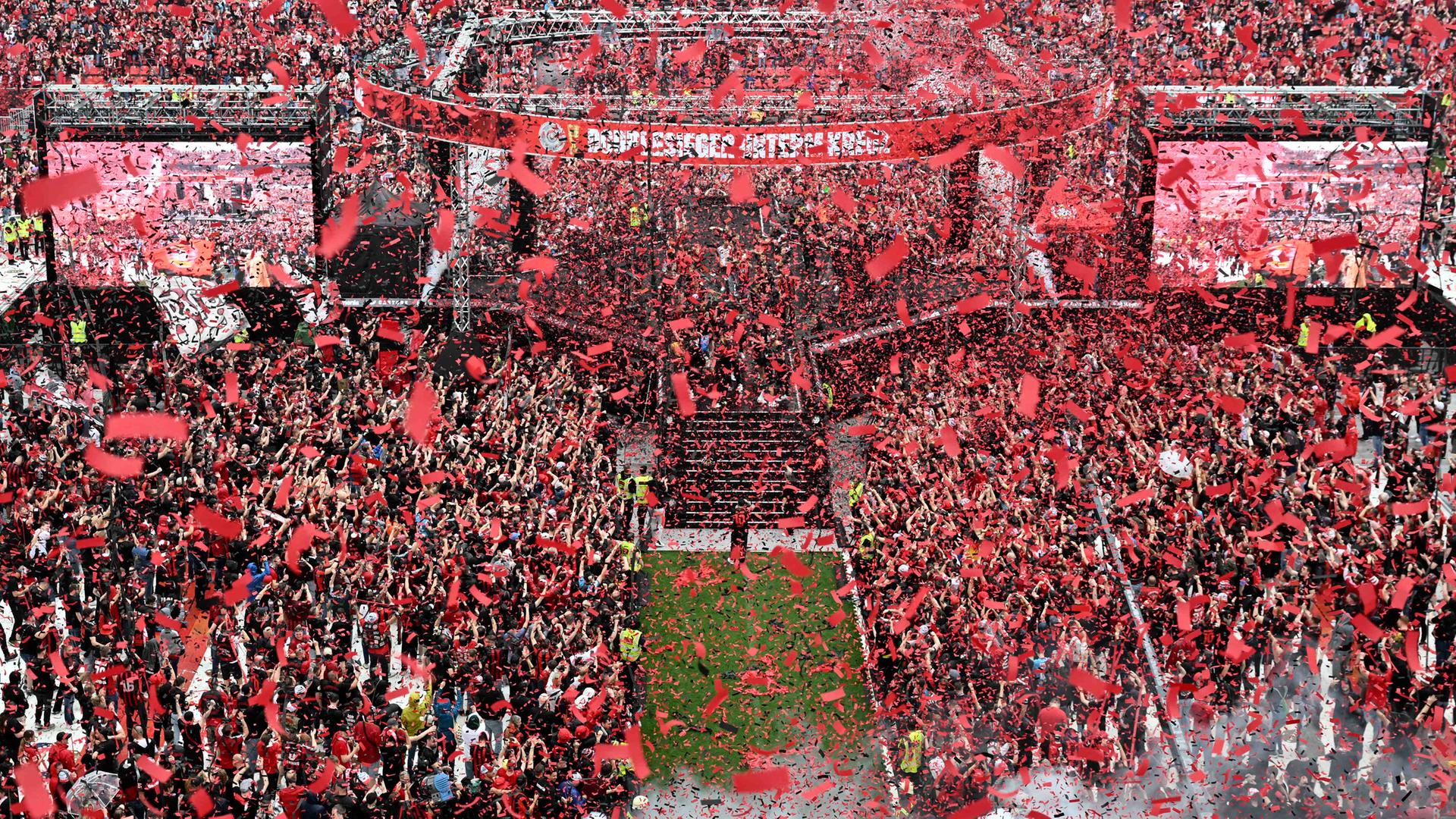 Spieler und Fans von Bayer Leverkusen feiern den Gewinn der Bundesliga und des DFB-Pokals im Stadion während der Siegesfeier.