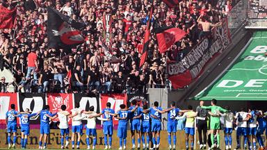 Die Spieler von Bayer Leverkusen feiern den Sieg mit den Fans im Stadion.