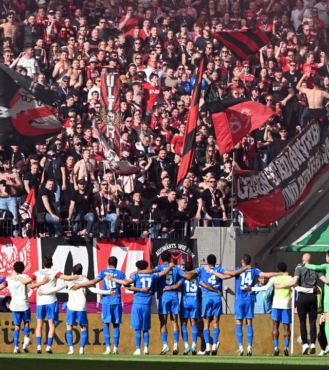 Die Spieler von Bayer Leverkusen feiern den Sieg mit den Fans im Stadion.