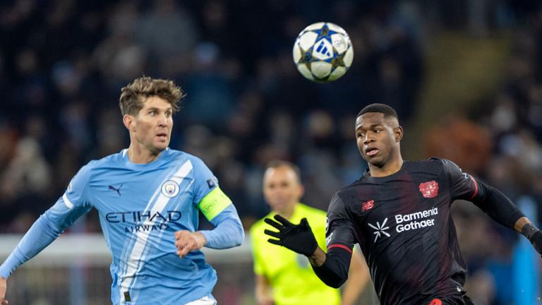 John Stones (Manchester City) und Christian Kofane (Bayer Leverkusen) kämpfen. 