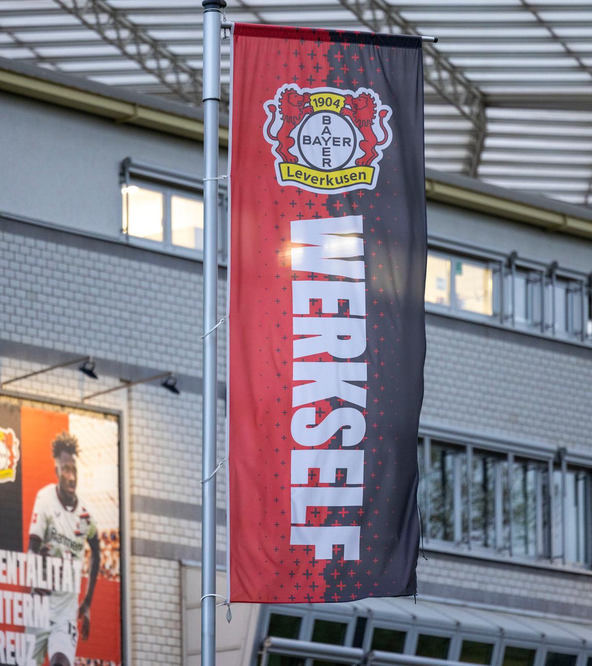 Eine Flagge mit den Farben und dem Wappen von Bayer 04 Leverkusen und der Aufschrift "Werkself" vor der BayArena.