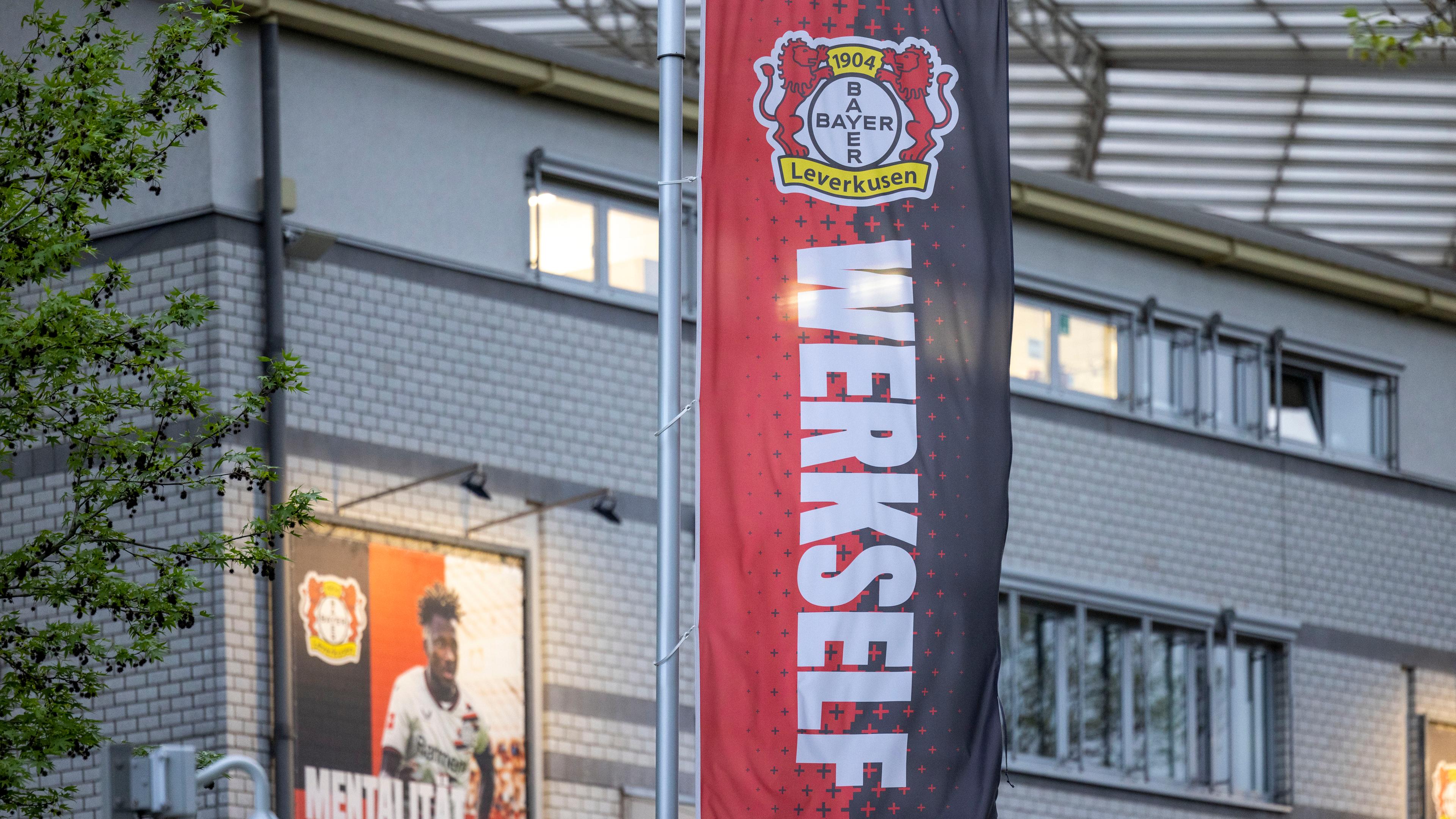 Eine Flagge mit den Farben und dem Wappen von Bayer 04 Leverkusen und der Aufschrift "Werkself" vor der BayArena.