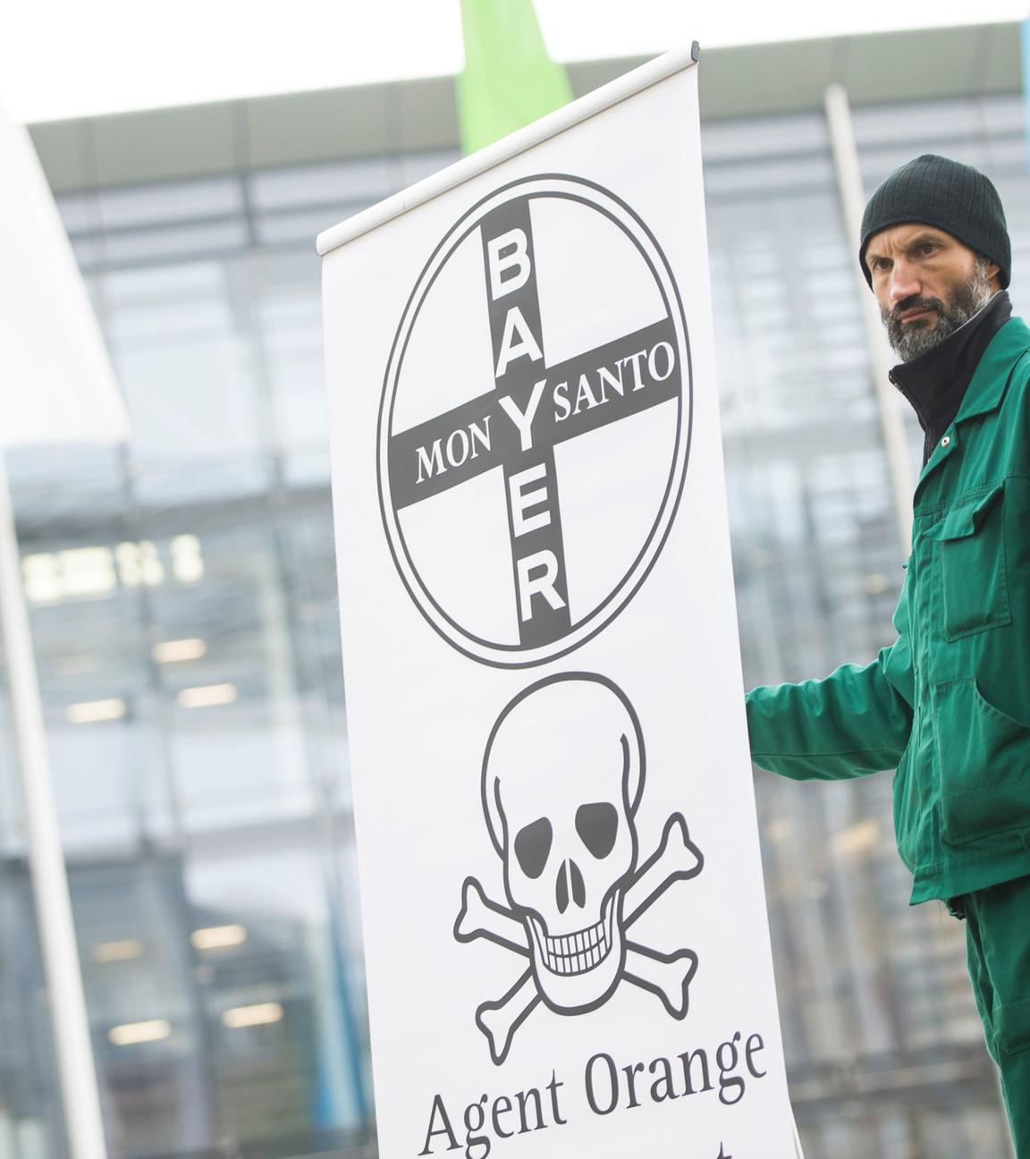 Landwirt protestiert von der Bayer-Zentrale mit einem Plakat 
