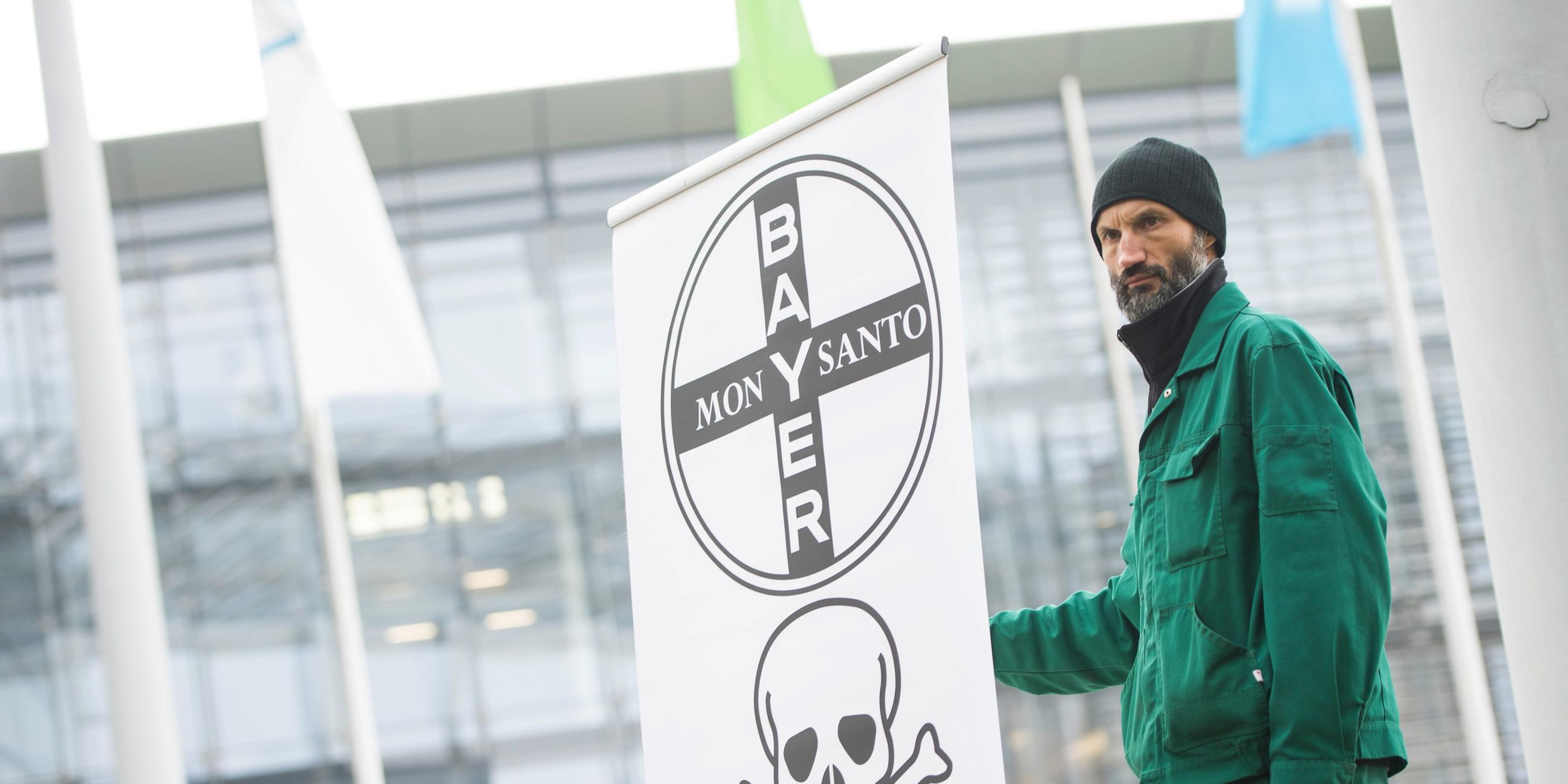 Landwirt protestiert von der Bayer-Zentrale mit einem Plakat 