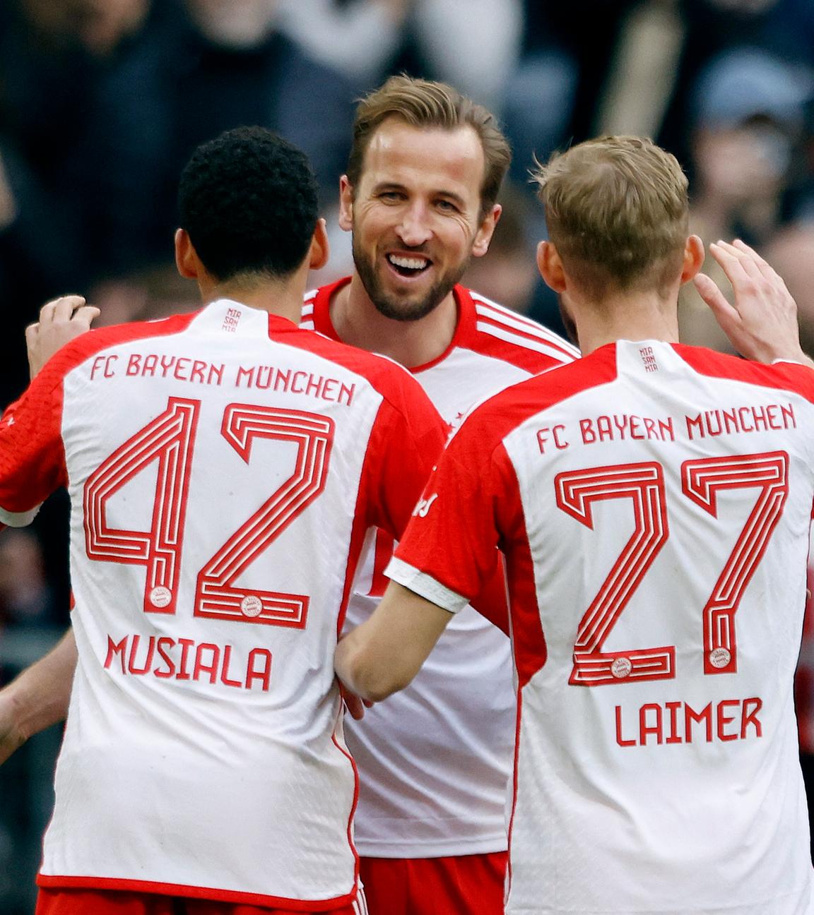 Münchens Harry Kane jubelt mit Jamal Musiala und Konrad Laimer beim Spiel gegen Mainz am 09.03.2024.