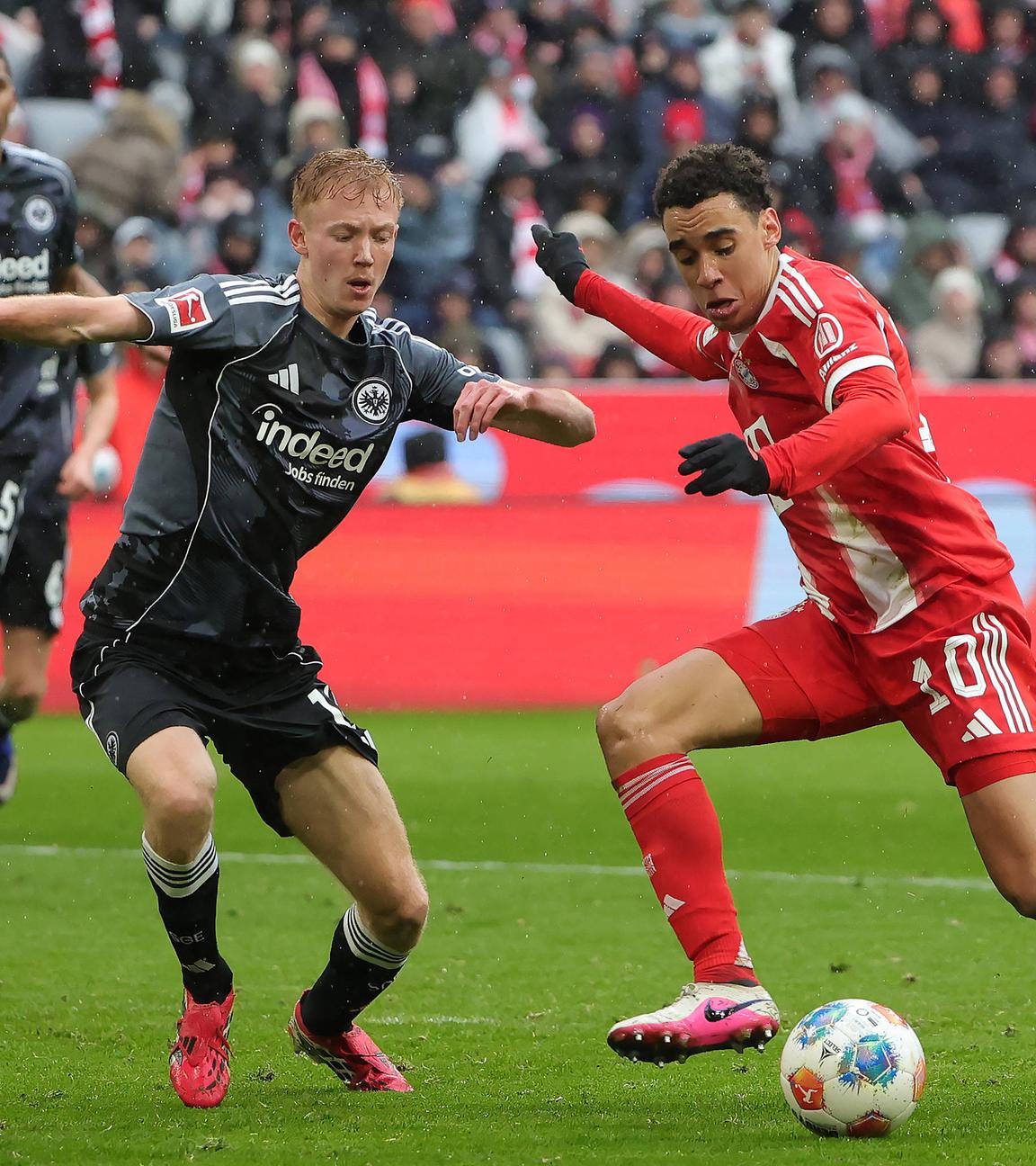 Hugo Larsson (Eintracht Frankfurt) und Jamal Musiala (FC Bayern München) kämpfen. 