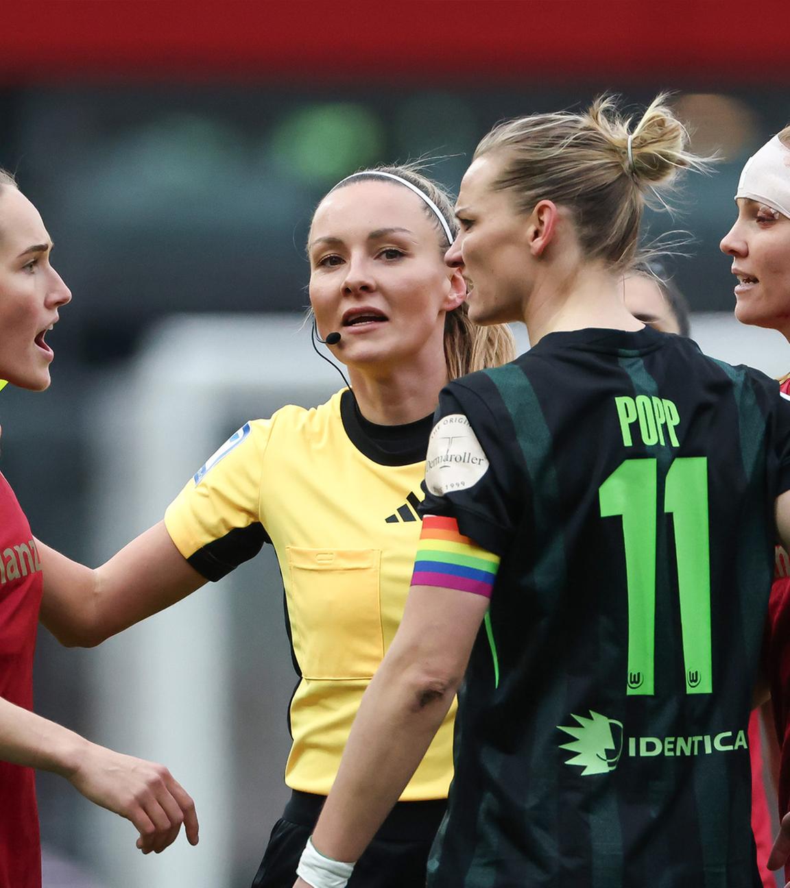 Sydney Lohmann (l., FC Bayern) und Alexandra Popp (2.v.r., VfL Wolfsburg) im hitzigen Austausch, während Schiedsrichterin Fabienne Michel (2.v.l.) dazwischengeht.