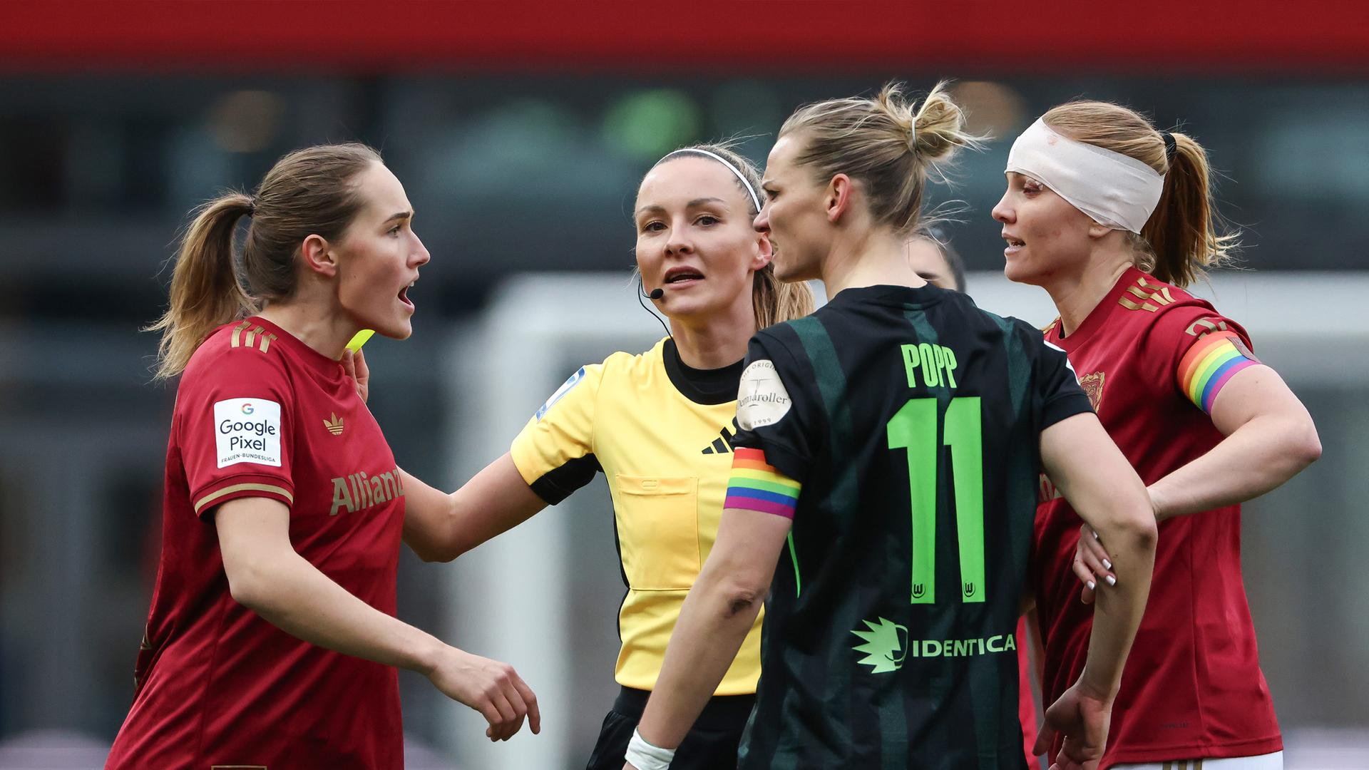 Sydney Lohmann (l., FC Bayern) und Alexandra Popp (2.v.r., VfL Wolfsburg) im hitzigen Austausch, während Schiedsrichterin Fabienne Michel (2.v.l.) dazwischengeht.