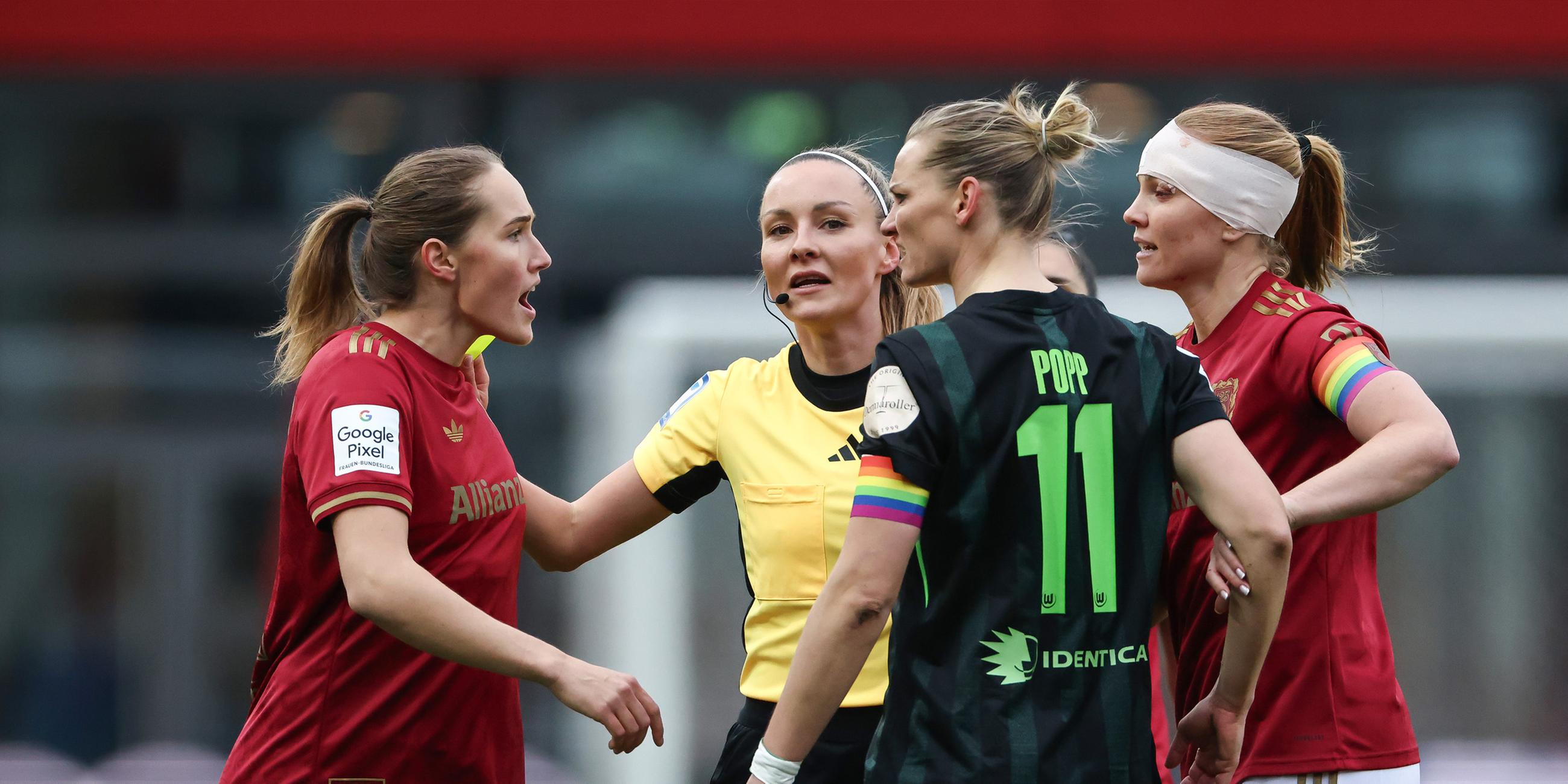 Sydney Lohmann (l., FC Bayern) und Alexandra Popp (2.v.r., VfL Wolfsburg) im hitzigen Austausch, während Schiedsrichterin Fabienne Michel (2.v.l.) dazwischengeht.