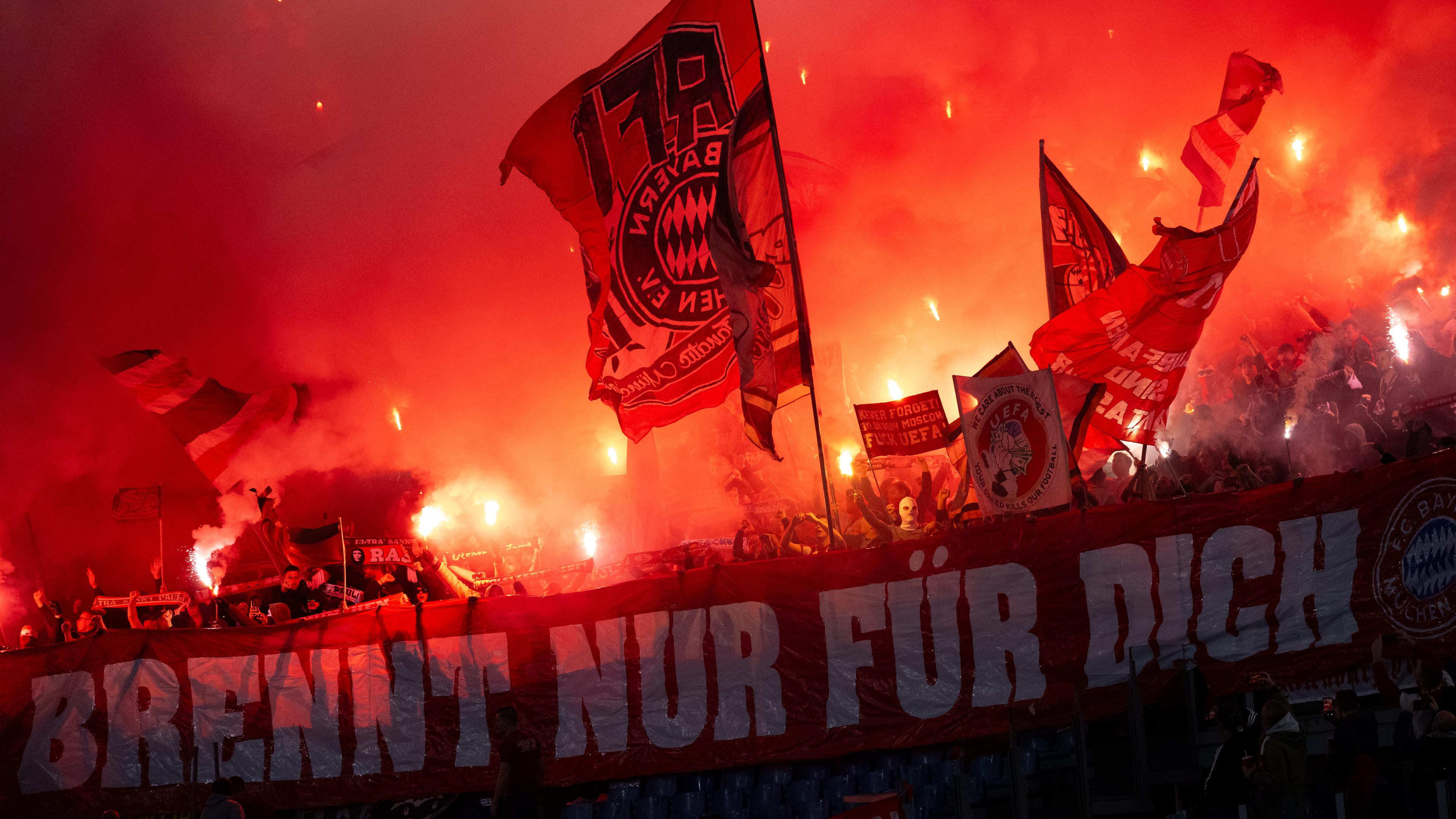 Fußball-Champions-League 2023/24, Lazio Rom - Bayern München, Achtelfinale, Hinspiel: Fans von Bayern München schwenken Fahnen und brennen Pyrotechnik ab.
