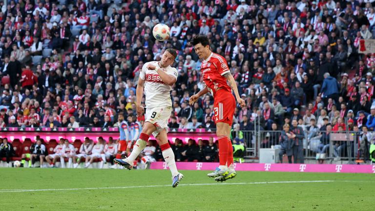 Ermedin Demirovic (VfB Stuttgart) und Minjae Kim (FC Bayern München) springen Seite an Seite in Richtung Ball