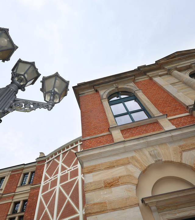 Untersicht auf das Festpielhaus-Gebäude und eine historische Straßenlaterne in Bayreuth.