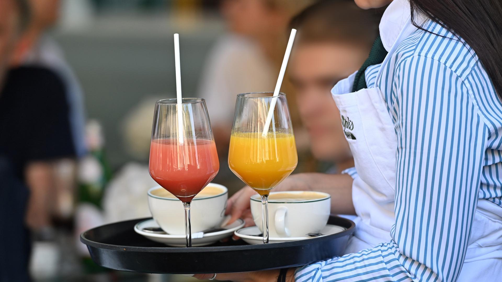 Eine Kellnerin trägt ein Tablett, auf dem zwei Cocktails stehen.