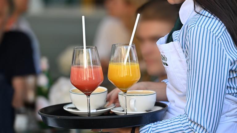Eine Kellnerin trägt ein Tablett, auf dem zwei Cocktails stehen.