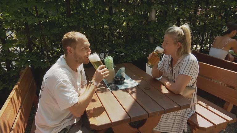 Besucher im Biergarten trinken Bier.