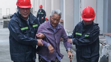 Ein älterer Mensch wird in eine Notunterkunft im Yangliu New Village, China, am 11.07.2026 begleitet.