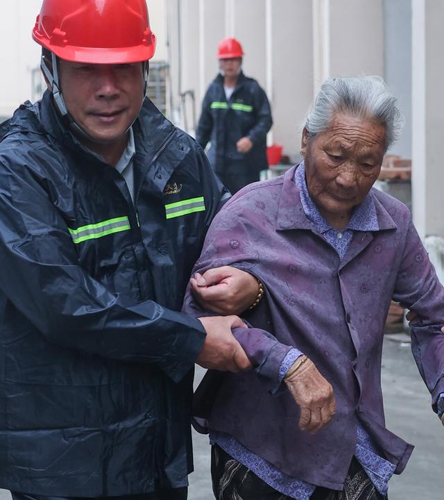 Ein älterer Mensch wird in eine Notunterkunft im Yangliu New Village, China, am 11.07.2026 begleitet.
