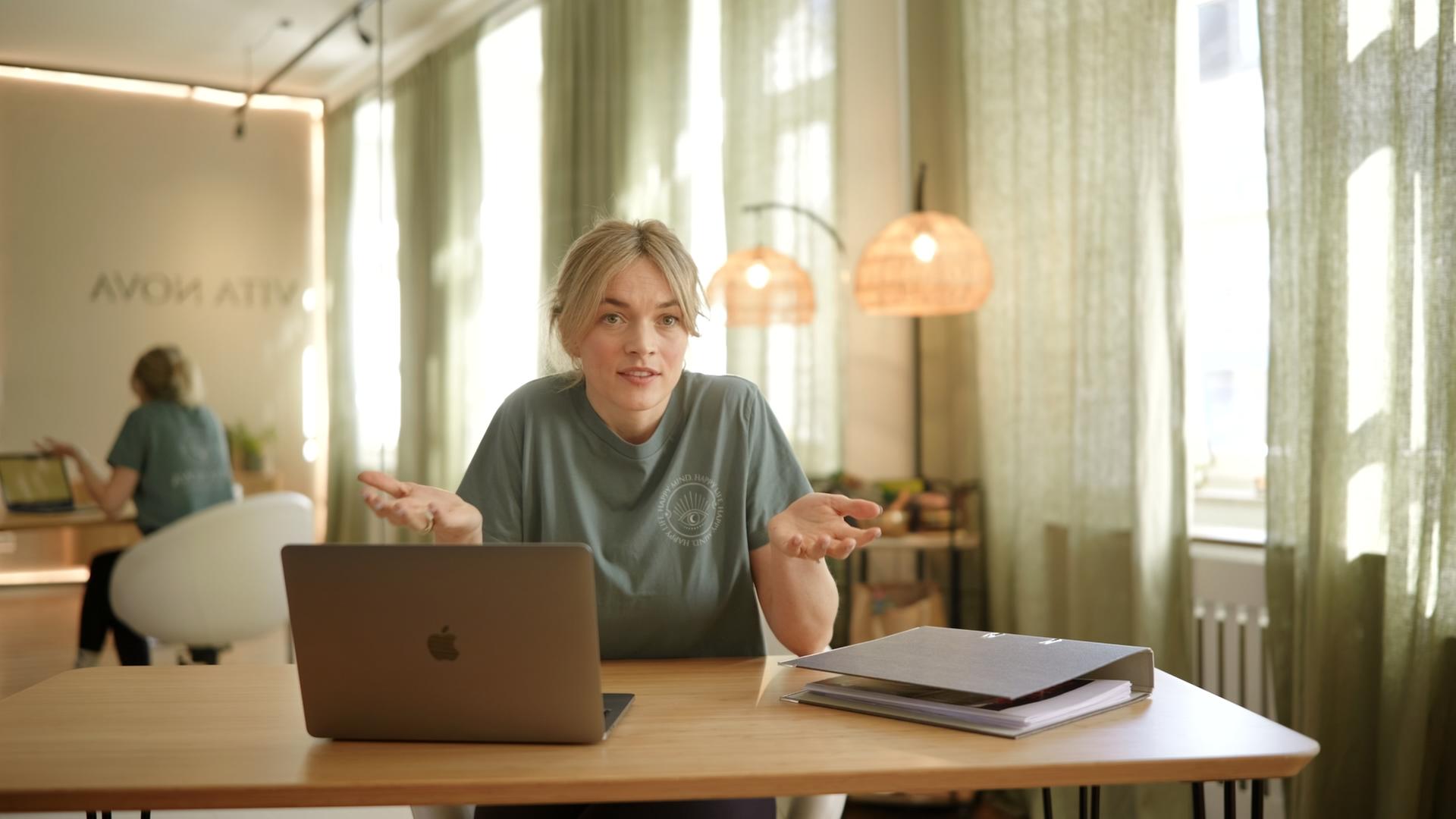 Hannah Lena Weber sitzt vor ihrem am Schreibtisch und hebt fragend die Hände